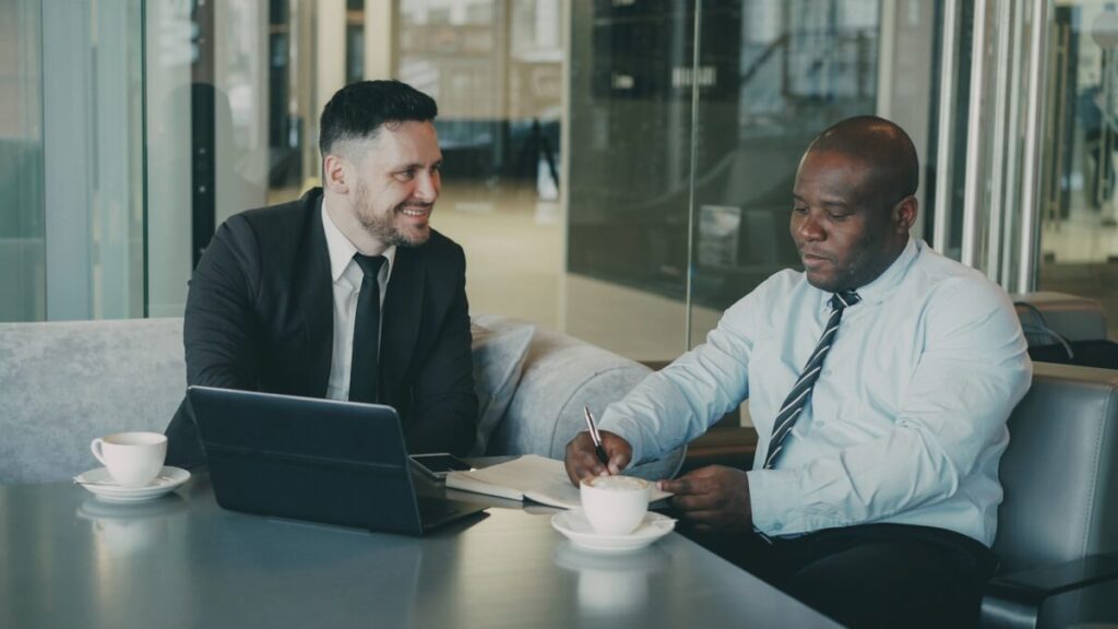 書類にサインする黒人男性とそれを見ているエージェント